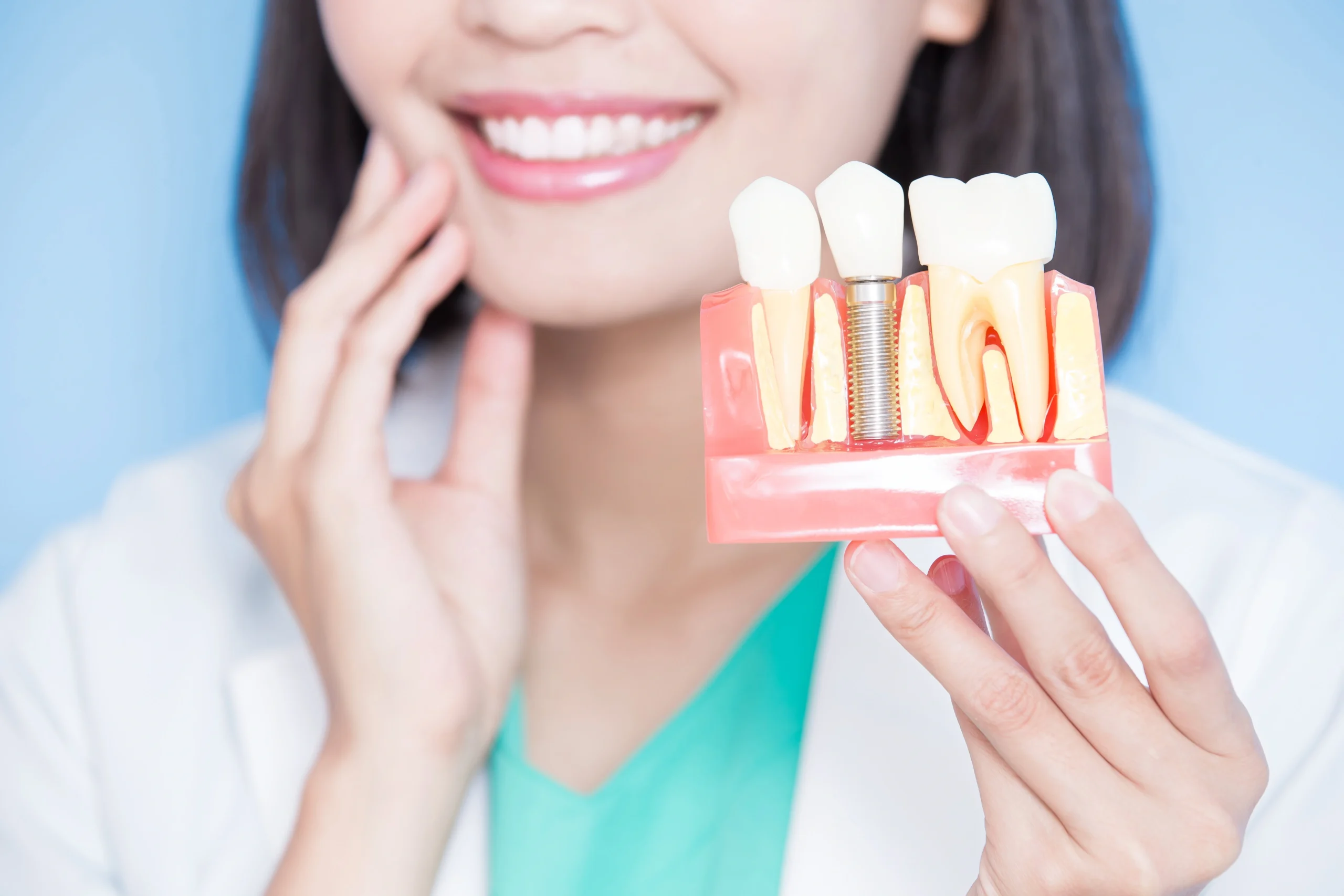 Woman showing dental implant model | Boger Dental | Plymouth, MN