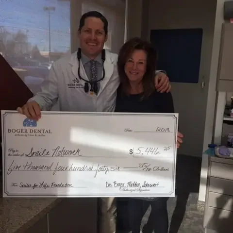 a man and woman dentist holding a large check | Boger Dental | Plymouth, MN